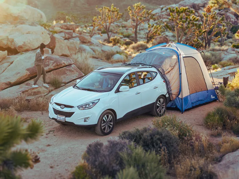 Family camping in the desert with their Napier Sportz SUV tent attached to their white SUV