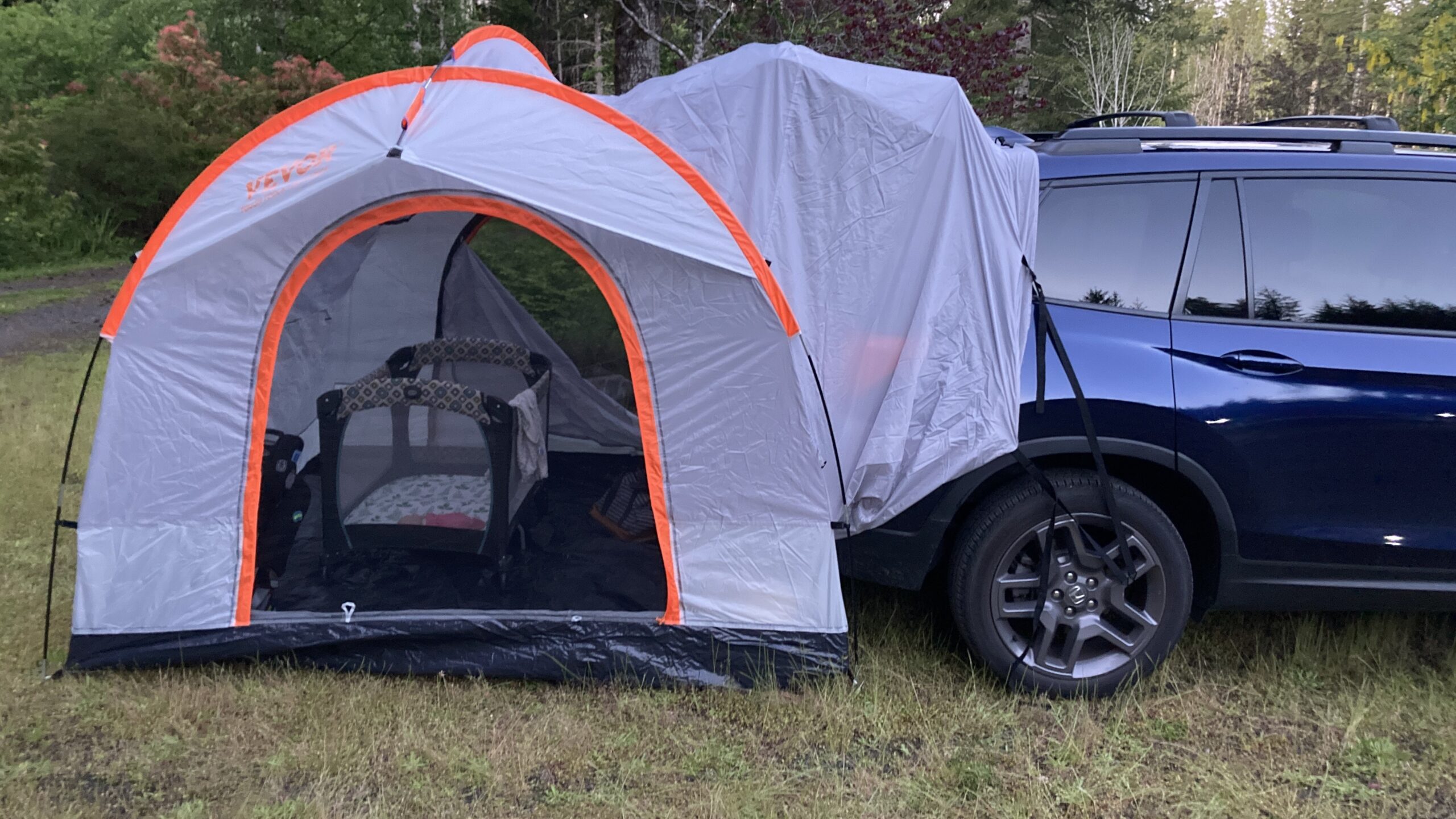 The toddler's crib on the tent floor at dusk, through the open door